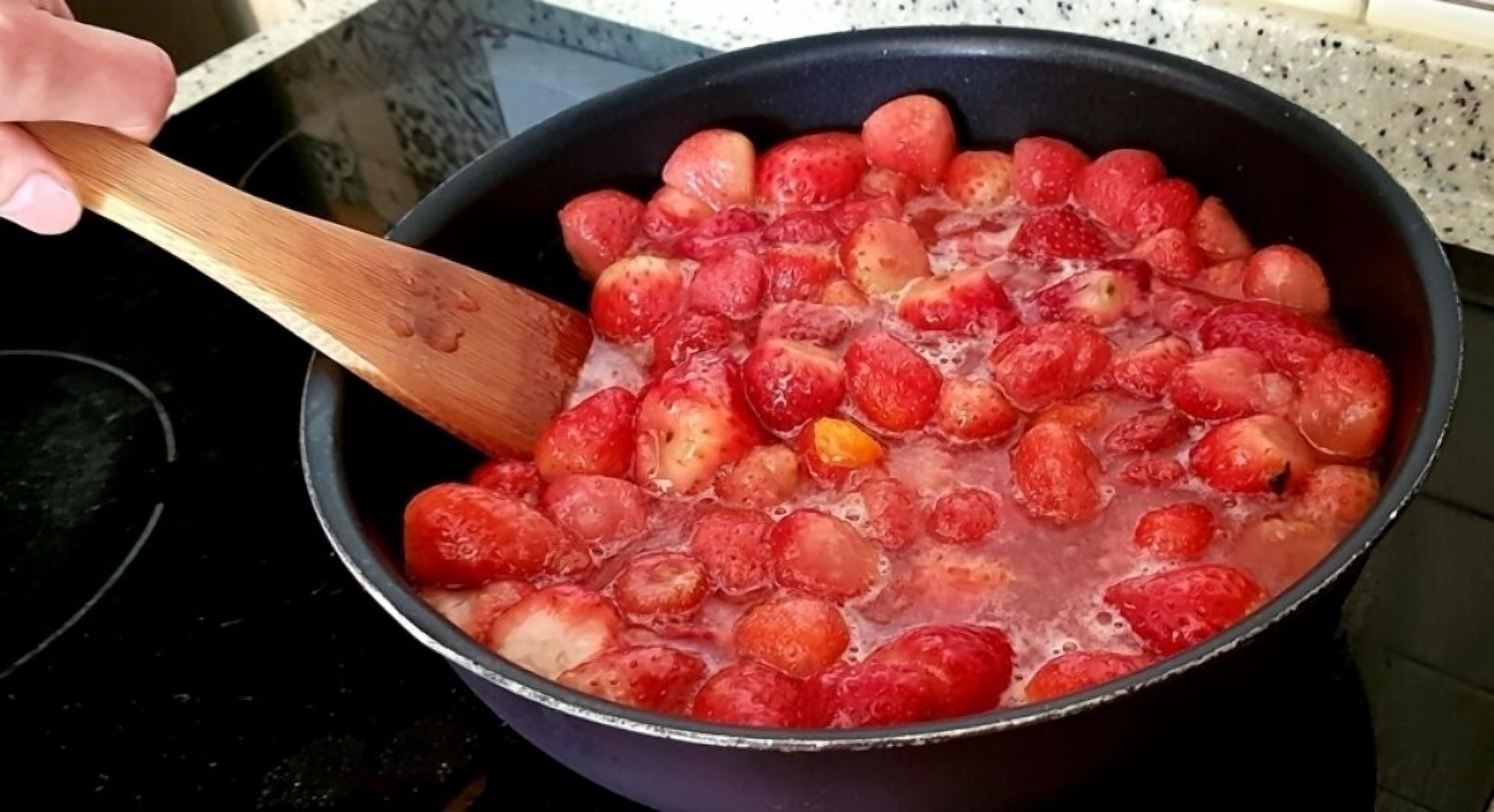 A person stirring a pot of strawberries.