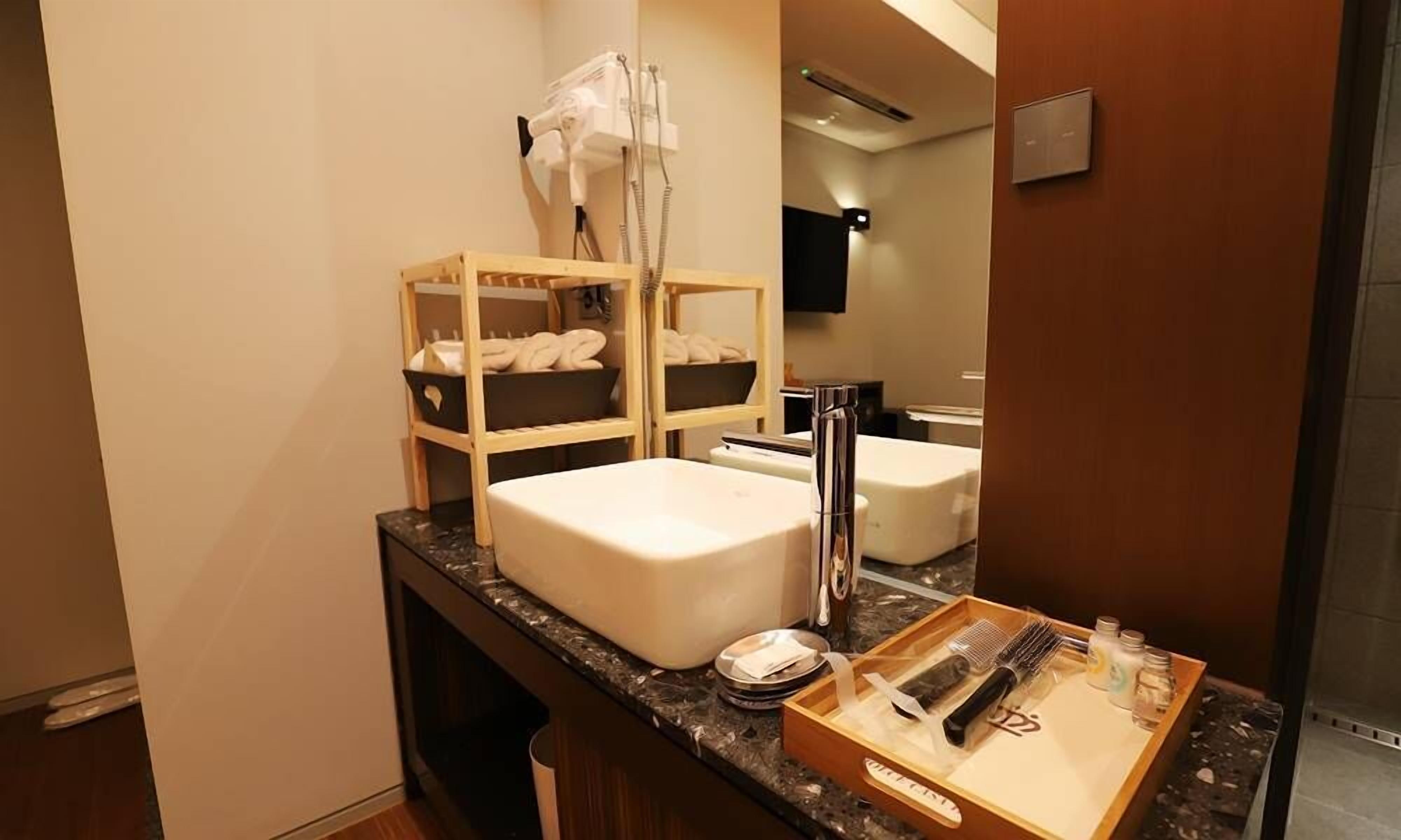 A bathroom with a large sink, a mirror, and a towel rack.