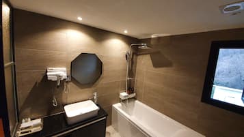 A modern bathroom with a large bathtub, a vanity with a sink, and a shower area.