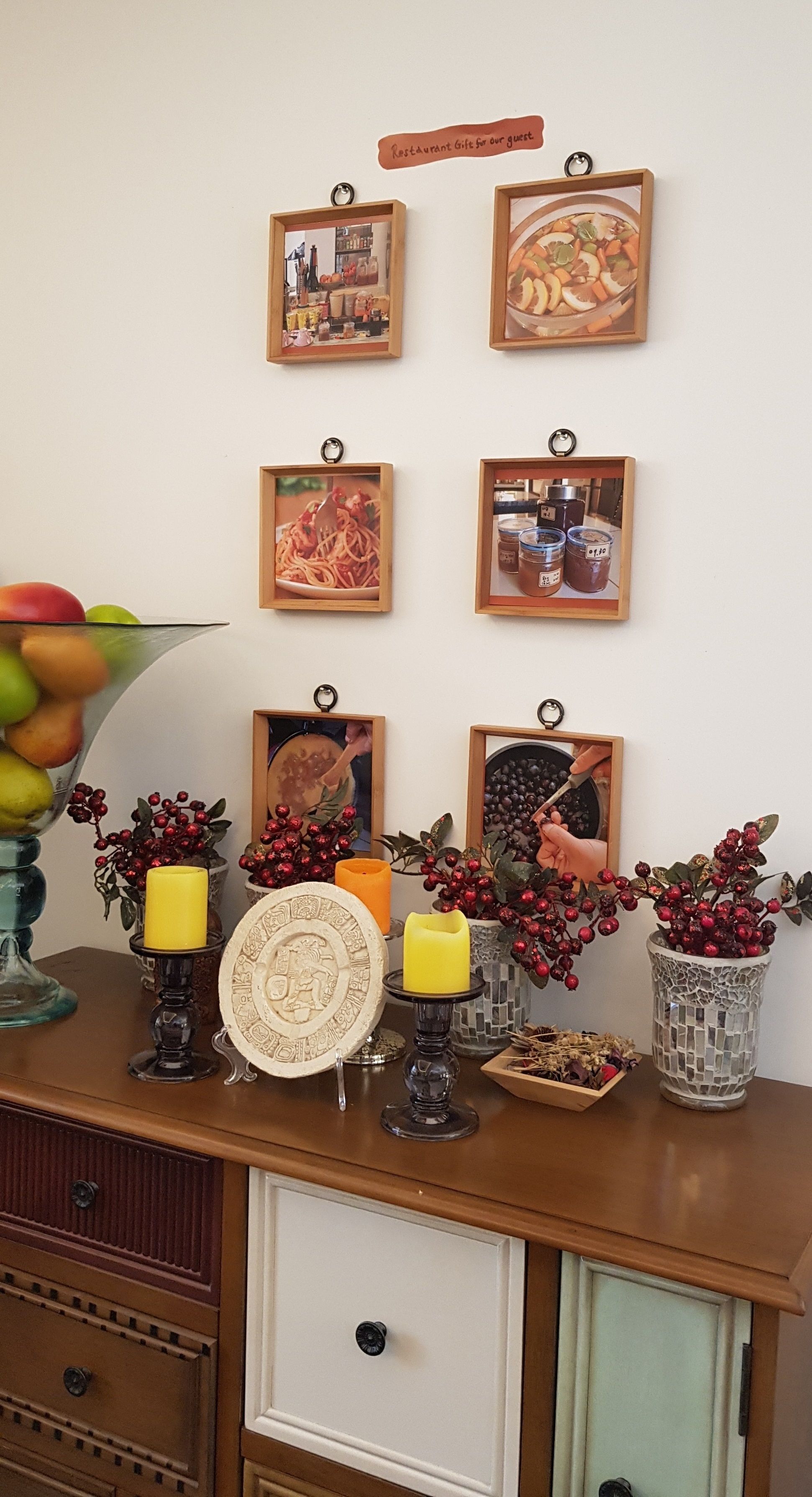 Une table en bois ornée de cadres contenant des photos, de bougies et d’objets décoratifs.