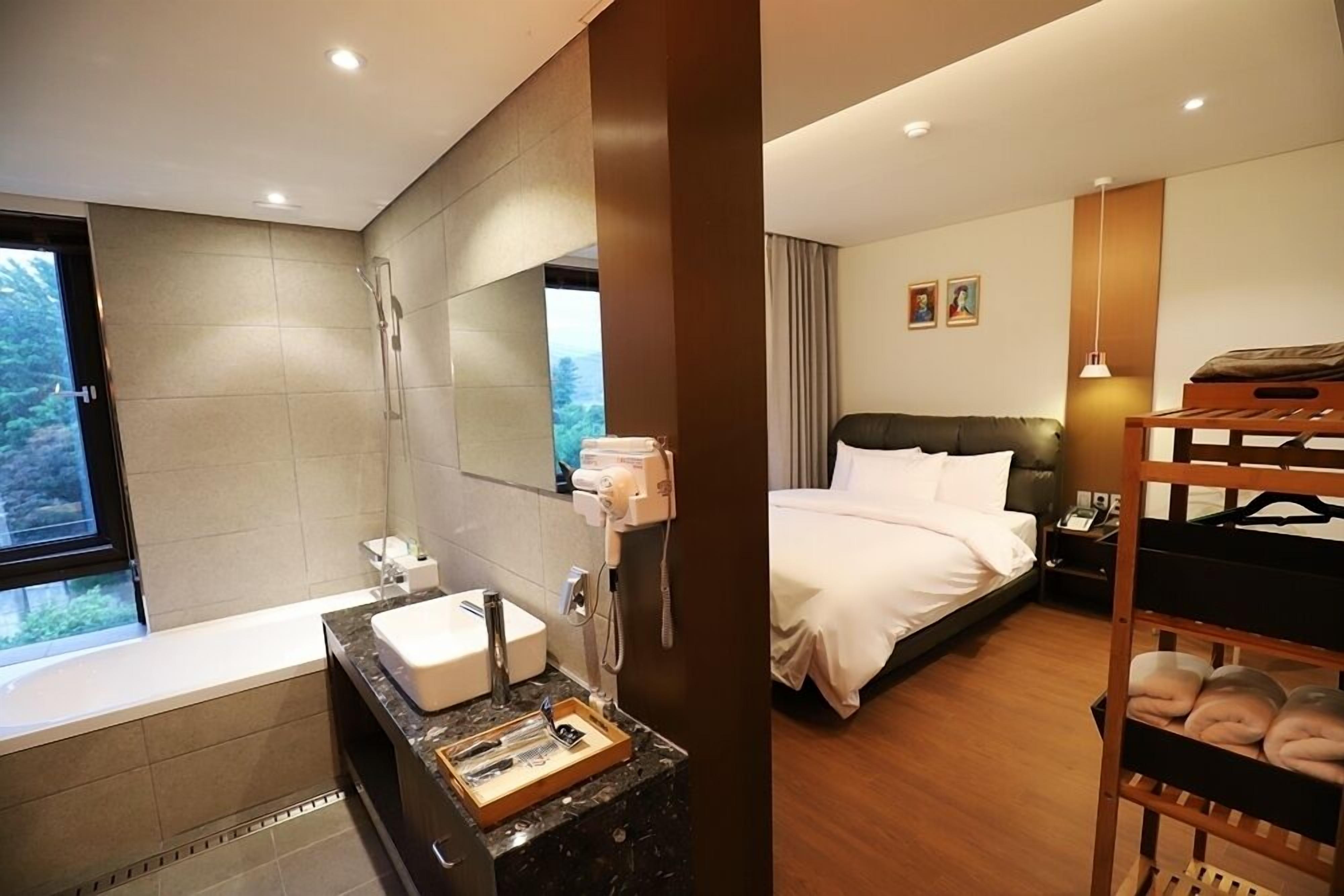 A modern hotel room with a large bed, a separate bathroom, and a view of the outdoors.