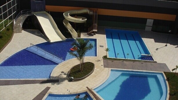 Ein Poolbereich mit mehreren Schwimmbecken, einer Wasserrutsche und einem kleinen Garten.