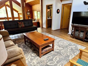 Una sala de estar acogedora con un sofá, una mesa de centro, un mueble para televisión y una alfombra estampada.