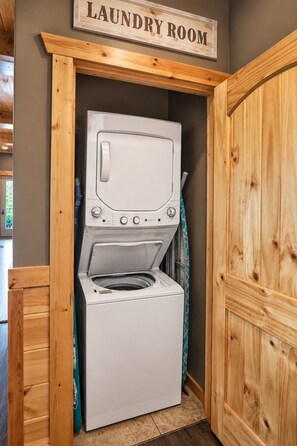 Un cuarto de lavandería con lavadora y secadora, armarios de madera y un cartel sobre los electrodomésticos.