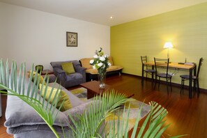 A living room with a sofa, a dining table with chairs, a lamp, and a vase with flowers. - Spacious, modern, GREAT LOCATION netflix, wifi, cable, 2BEDROOM, 2BATHROOM (La Carolina)