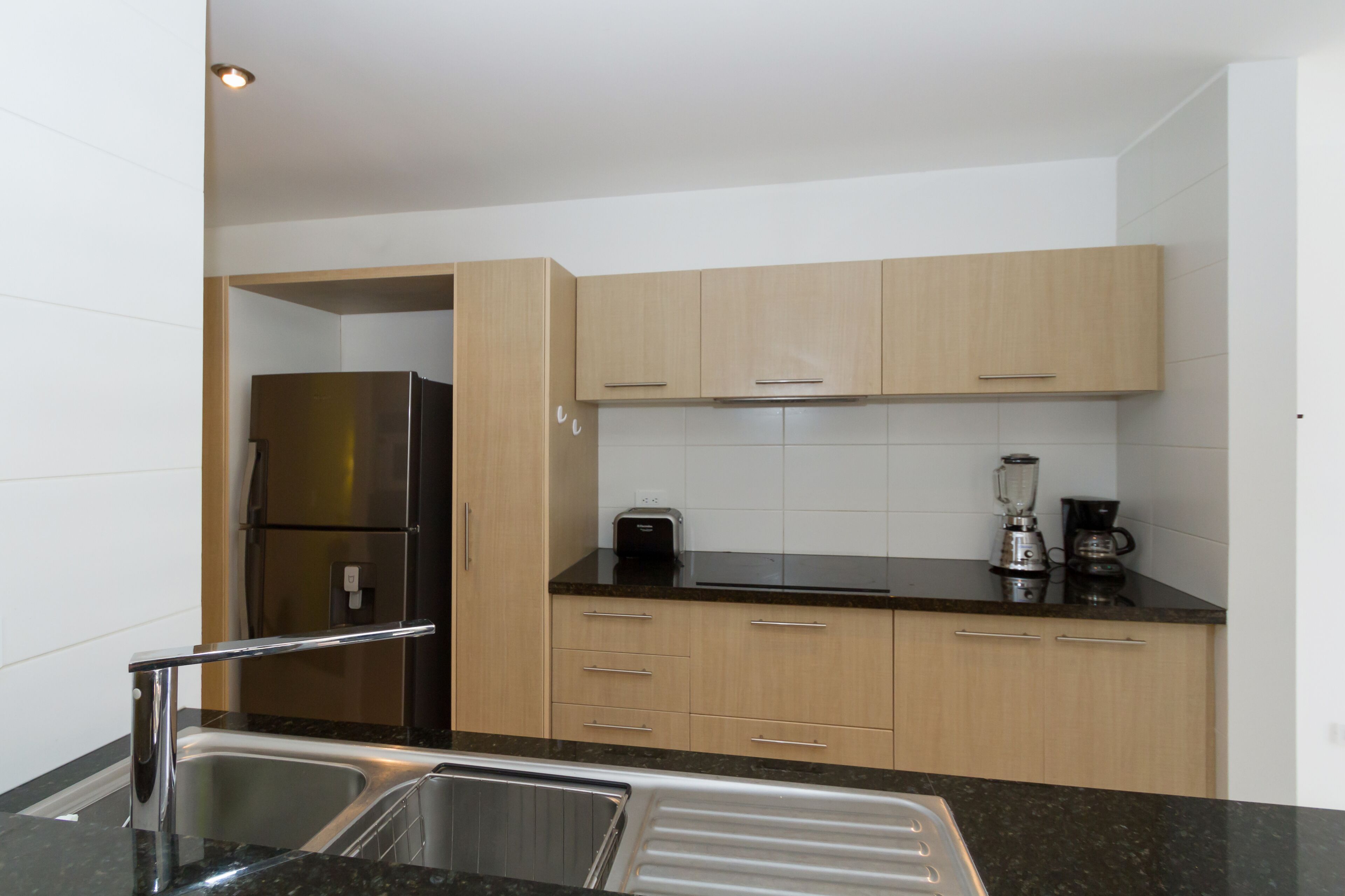 A modern kitchen with stainless steel appliances, wooden cabinets, and a black countertop.