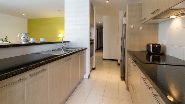 A modern kitchen with a black countertop, stainless steel appliances, and light wood cabinets. - Spacious, modern, GREAT LOCATION netflix, wifi, cable, 2BEDROOM, 2BATHROOM (La Carolina)