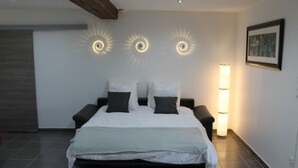 Ein Schlafzimmer mit Bett, Nachttischen und Wandleuchten.