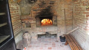 Ein Kamin aus Backsteinen mit Feuer, eine Holzbank und ein Fliesenboden.
