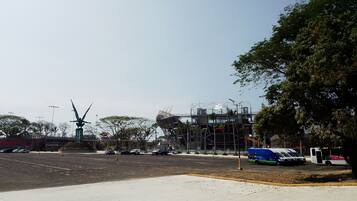 A parking lot with a few cars, a large sculpture, and a building under construction.
