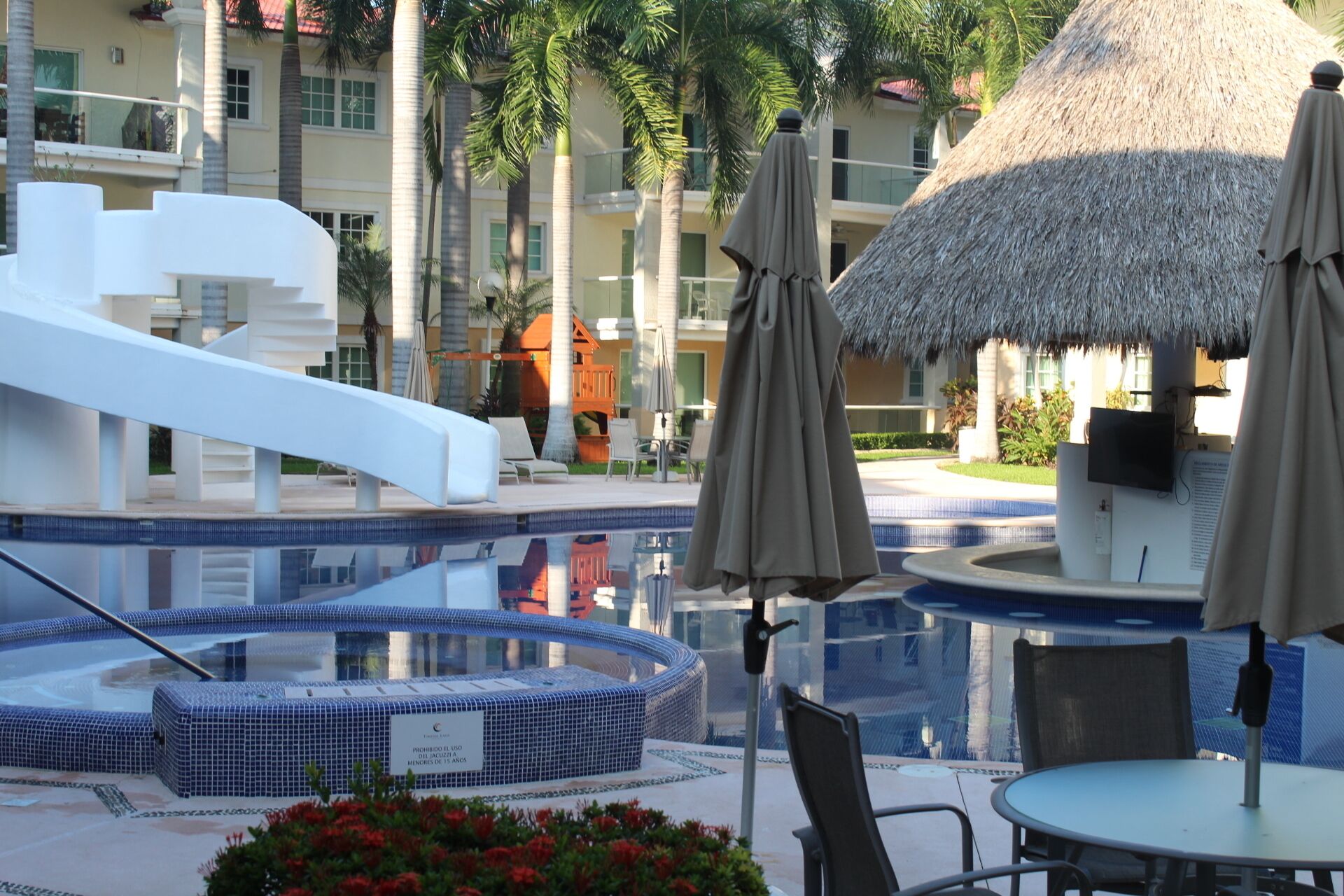 A pool area with a slide, lounge chairs, and umbrellas. - Nice Apartment, perfect for families!  (Diamante Lakes)