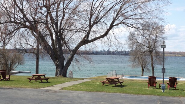 A park with picnic tables and benches by a lake. - Windjammer Lodge (Ogdensburg)