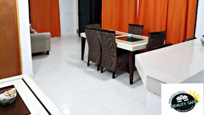 Een eetgedeelte met een tafel en stoelen, oranje gordijnen, een bank en een schaal op een tafel.