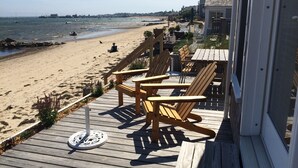 A wooden deck with Adirondack chairs overlooking a sandy beach and the ocean. - Living on the edge! Breathtaking waterfront living at it’s best!  (Provincetown)