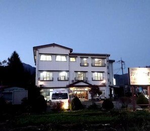A two-story building with multiple windows, a covered entrance, and a parked van in front. - Resort Inn Fujihashi (Fujikawaguchiko)