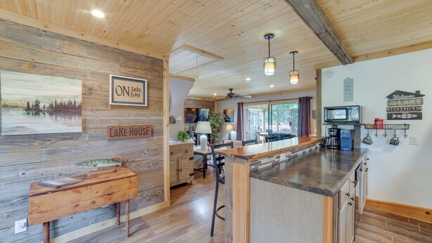 Una cocina con muebles de madera, una barra y un comedor con mesa de madera.