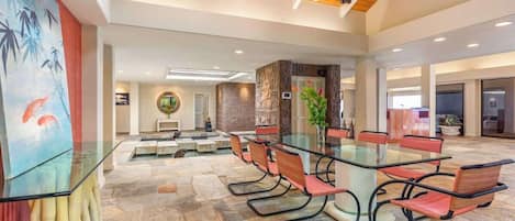 A spacious conference room with a glass table and modern chairs, a wooden ceiling, and a stone floor.