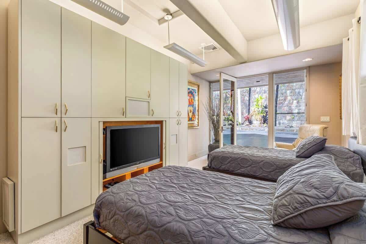 Una camera da letto con due letti, una televisione e un ampio guardaroba.