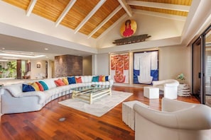 A spacious living room with a large sectional sofa, a glass coffee table, and a white armchair.