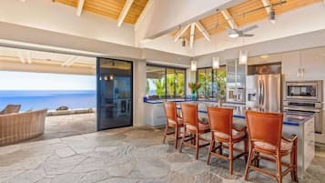 A modern kitchen with a large island, stainless steel appliances, and a view of the ocean.