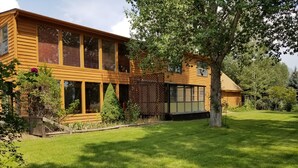 Ein zweistöckiges Holzhaus mit großen Fenstern und einem gepflegten Rasen.