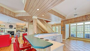 A spacious kitchen with a central island, wooden ceiling, and large windows. - Cordy Beach House - 2nd Row Ocean View, Gated with Pool! (Pawleys Island)