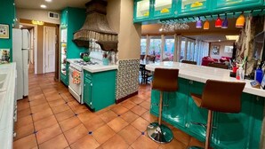 Cozinha com armários verde-água, fogão a gás e um balcão com banquetas.