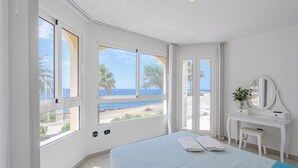 A bedroom with a bed, a desk, and a large window with a view of the beach and ocean. - ..it's your place!... (Los Cristianos)
