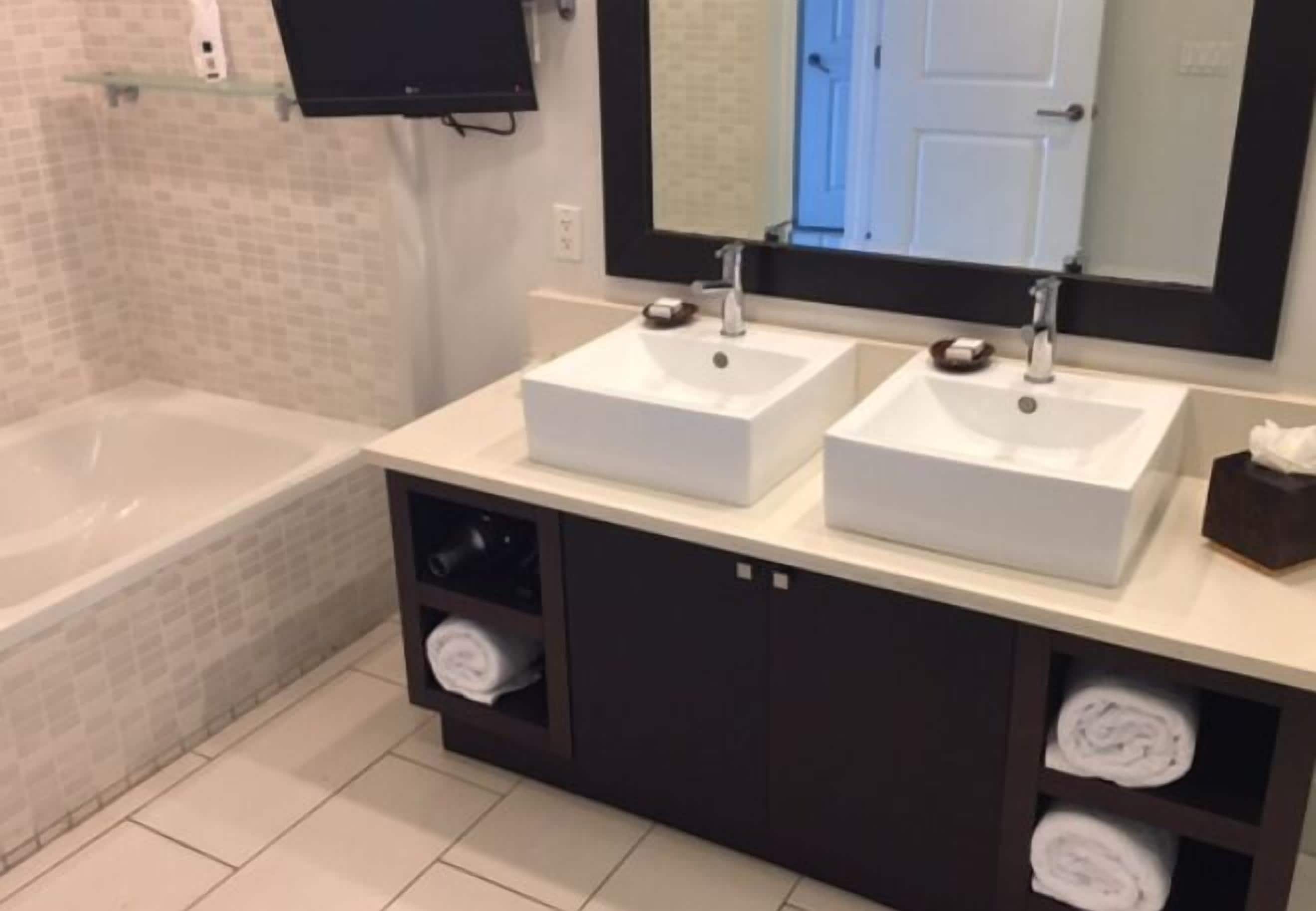 A bathroom with two sinks, a bathtub, and a mirror above the sinks.
