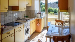 Une cuisine compacte équipée d’un lave-linge, d’une table à manger avec des chaises et offrant une vue sur l’extérieur grâce à une fenêtre.