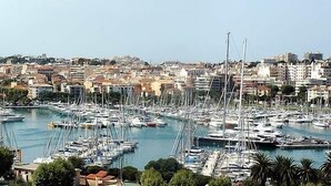 Un port de plaisance où sont amarrés de nombreux bateaux, entouré d’un quartier urbain densément bâti, composé d’un mélange de bâtiments résidentiels et commerciaux.