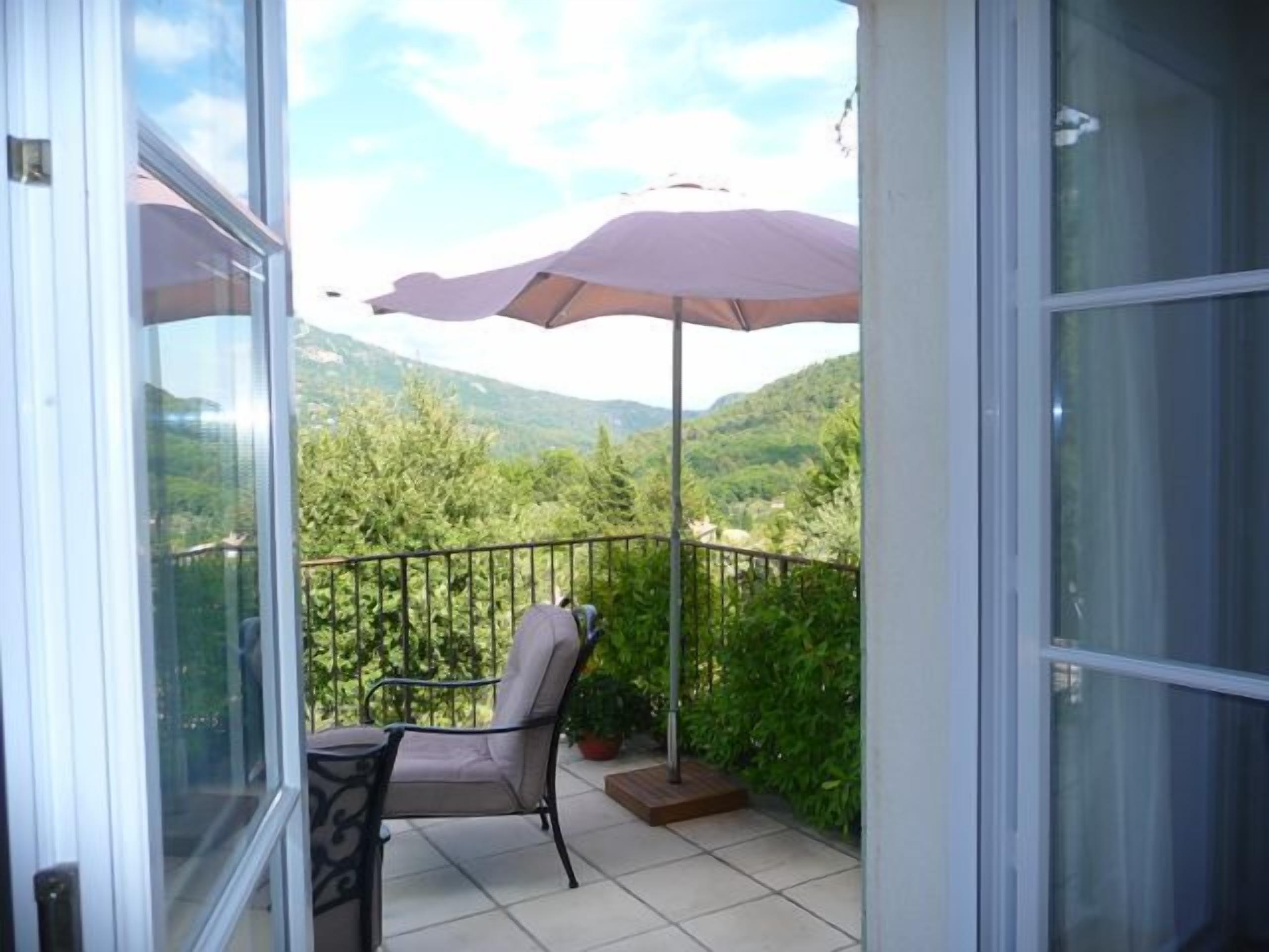 Ein Balkon mit Stuhl und Sonnenschirm, mit Blick auf eine Berglandschaft.