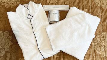 A neatly folded white shirt, a white towel, and a tube of Sanitary soap on a patterned brown bedspread.