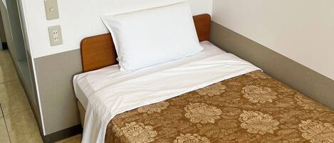 A small bed with a wooden headboard, white bedding, and a brown floral-patterned bedspread.