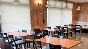 A restaurant with multiple tables and chairs, wooden walls, and pendant lighting. - Hotel Yamadasou (Nago)