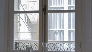 Un comedor con una mesa dispuesta para cuatro personas, una ventana con vista a un edificio y una puerta con manija.