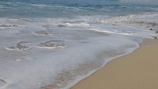 Une plage où les vagues viennent doucement lécher le rivage.
