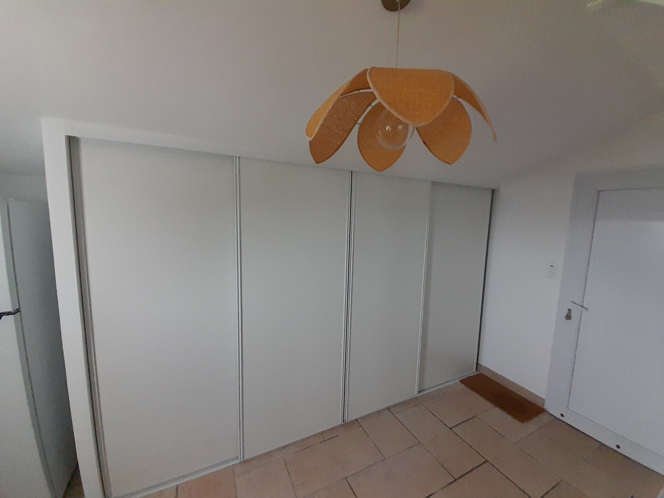 Ein Zimmer mit Schiebetürenschrank, Fliesenboden und Pendelleuchte.