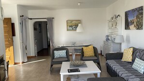 A modern living room with a sofa, a coffee table, and a dining area with a glass table.