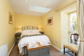 Ein Hotelzimmer mit einem Bett, Nachttischen, einem Sessel und einem Fenster mit Vorhängen.