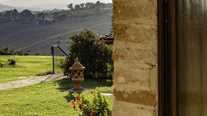 A view from a window overlooking a grassy landscape with a stone wall, a small garden, and distant hills. - QUERCIA apartment, 210 sqm with shared swimming pool (Santa Maria Nuova)