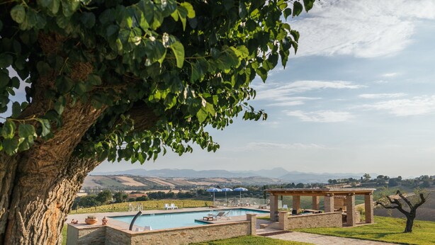 A pool area with lounge chairs, a pergola, and a view of rolling hills. - QUERCIA apartment, 210 sqm with shared swimming pool (Santa Maria Nuova)