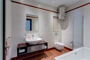 A modern bathroom with a white sink, mirror, and toilet, a glass shower enclosure, and a wooden vanity. - Seaview Apartment In Fort Cambridge, Sliema (Sliema)