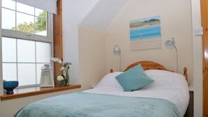 Une chambre à coucher avec un lit, une fenêtre, un tableau et une table de chevet avec une lampe.