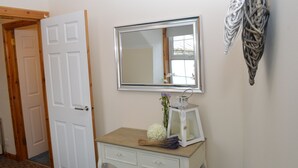 Une pièce comprenant une commode en bois, un miroir, une lanterne blanche et un élément décoratif mural.