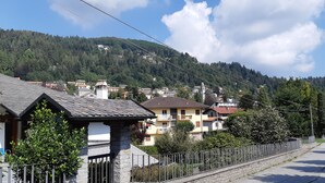 A residential street with houses, a stone fence, and a mountain backdrop. - Camellia, suggestions between Lake and mountains (Premeno)