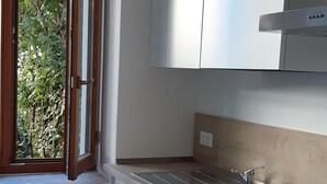 A modern kitchen with white cabinetry, a stainless steel sink, and a built-in oven. - Camellia, suggestions between Lake and mountains (Premeno)