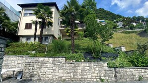 A swimming pool with stone steps leading up to it, surrounded by a stone wall and lush greenery. - Nice apartment in villa with WIFI, private pool, TV, terrace, pets allowed and panoramic view (Lugano)
