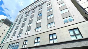 A multi-story hotel with a modern design, featuring a prominent entrance and a sign indicating it is a premium urban hotel. - Urban Hotel Kyoto Shijo Premium (Kyoto)