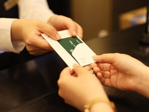 A person handing over a card to another person at a counter. - Urban Hotel Kyoto Shijo Premium (Kyoto)